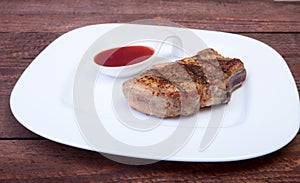 Grilled pork chop with Cranberry sauce on plate on wooden board