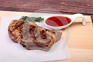 Grilled pork chop with Cranberry sauce on plate on wooden board