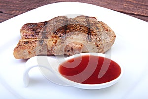 Grilled pork chop with Cranberry sauce on plate on wooden board