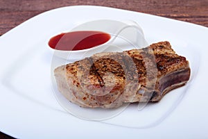 Grilled pork chop with Cranberry sauce on plate on wooden board