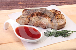 Grilled pork chop with Cranberry sauce on plate on wooden board