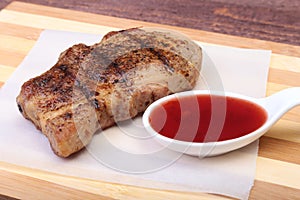 Grilled pork chop with Cranberry sauce on plate on wooden board