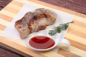 Grilled pork chop with Cranberry sauce on plate on wooden board