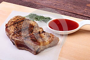 Grilled pork chop with Cranberry sauce on plate on wooden board