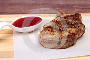 Grilled pork chop with Cranberry sauce on plate on wooden board