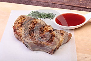 Grilled pork chop with Cranberry sauce on plate on wooden board