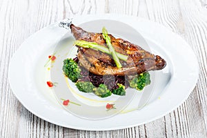 Grilled pork chop steak on the bone with asparagus and broccoli on light wooden background close up. Hot Meat Dishes