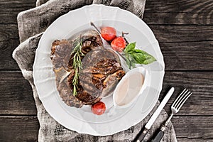 Grilled pork chop steak with rosemary, tomatoes and spices on wooden rustic background. Hot Meat Dishes