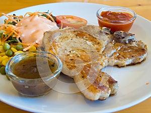 Grilled pork chops with vegetables, salad and dipping saurce