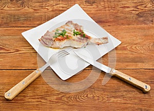 Grilled pork loin chop on dish with fork and knife