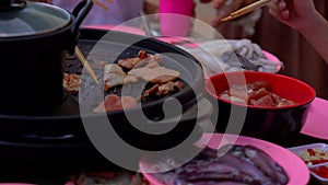 Grilled pork meat in chopsticks on hot steam smoke water from hot pan for cooking in party