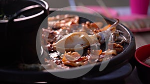 Grilled pork meat in chopsticks on hot steam smoke water from hot pan for cooking in party