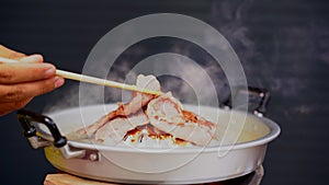 Grilled pork meat and seafood in chopsticks on hot steam smoke water from hot pan for cooking in party