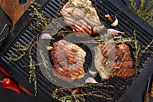 Grilled pork neck with aromatic herbs, garlic and chili peppers on a cast iron grill