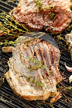 Grilled pork neck with herbs and garlic on a cast iron grill plate