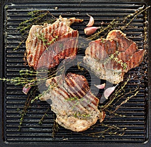 Grilled pork neck with herbs and garlic on a cast iron grill plate