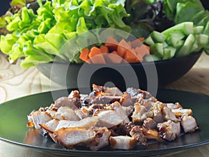 Grilled pork in a plate and Green leafy vegetables.