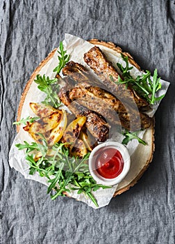 Grilled pork ribs and french fries on wooden board on grey background. Delicious lunch, appetizers, tapas