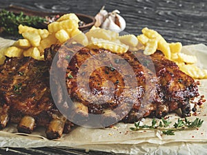 Grilled pork ribs with sauce on a cutting board, french fries