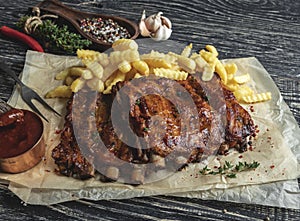 Grilled pork ribs with sauce on a cutting board, french fries