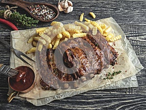 Grilled pork ribs with sauce on a cutting board, french fries