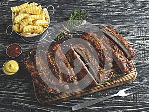 Grilled pork ribs with sauce on a cutting board, french fries