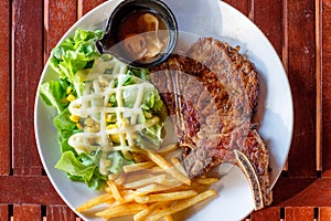 Grilled pork ribs steak well-done with french fries and vegetable