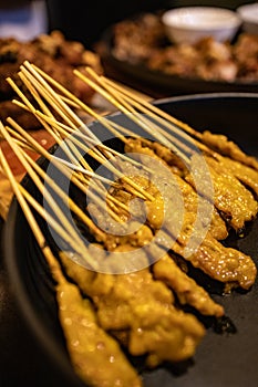 Grilled pork satay on the bamboo stick in a black tray