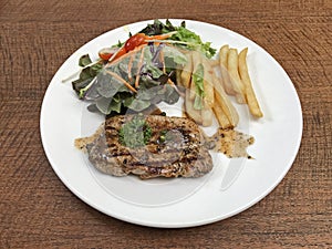 Grilled Pork Steak with black pepper sauce served with vegetables salad and frenchfries.