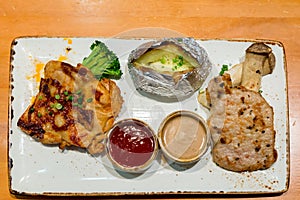 Grilled pork steak and Chicken steak, French fries and vegetables. Assorted meat from chicken and pork and various vegetables on b