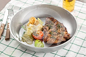 Grilled pork steak with mashed potato, pickles and glass of beer on the table