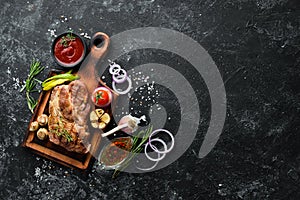 Grilled pork steak with spices on black stone background.