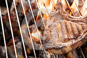 Grilled pork steaks over flames on the grill.