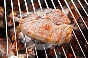 Grilled pork steaks over flames on the grill