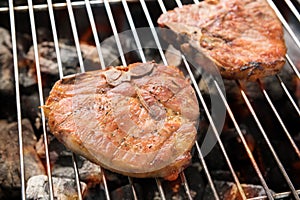 Grilled pork steaks over flames on the grill