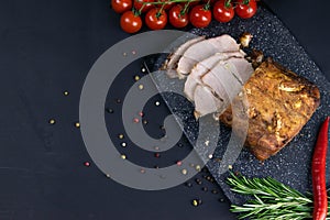 Grilled pork steaks and rosemary with hot paper and sauce on black stone background