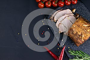 Grilled pork steaks and rosemary with hot paper and sauce on black stone background