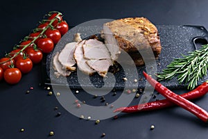 Grilled pork steaks and rosemary with hot paper and sauce on black stone background