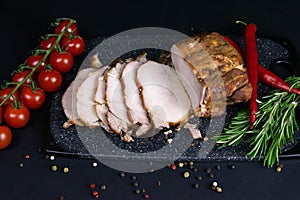 Grilled pork steaks and rosemary with hot paper and sauce on black stone background