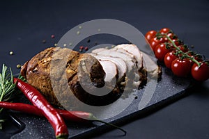 Grilled pork steaks and rosemary with hot paper and sauce on black stone background