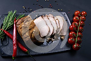 Grilled pork steaks and rosemary with hot paper and sauce on black stone background