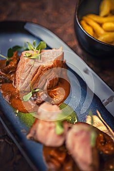 Grilled pork tenderloin with mushroom sauce served on plate with glass of wine and dumplings, modern seasonal gastronomy