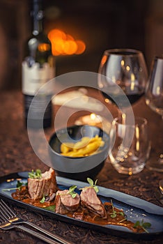 Grilled pork tenderloin with mushroom sauce served on plate with glass of wine and dumplings, modern seasonal gastronomy