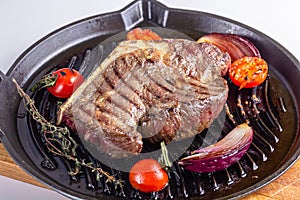Grilled premium rib eye beef steak in the pan, cooking steak in the kitchen on a dark background, top view