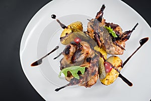 Grilled quail meat with vegetables on black background