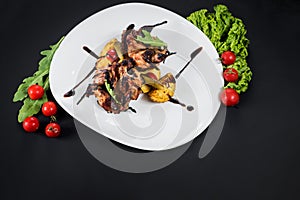 Grilled quail meat with vegetables on black background