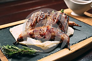 Grilled quails on the wooden plate on the table