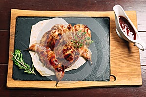 Grilled quails on the wooden plate on the table