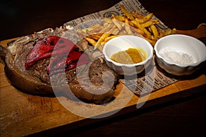 Grilled rare beef steak served on wooden board with fried potatoes photo