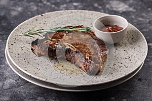 Grilled red beef pork meat barbecue steak fillet with rosemary sprig and hot sauce served on plate